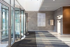 A side-by-side comparison of an automatic swing door and an automatic sliding glass door at modern commercial building entrances.