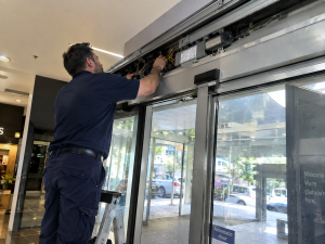 Automatic sliding door technician inspecting door operator